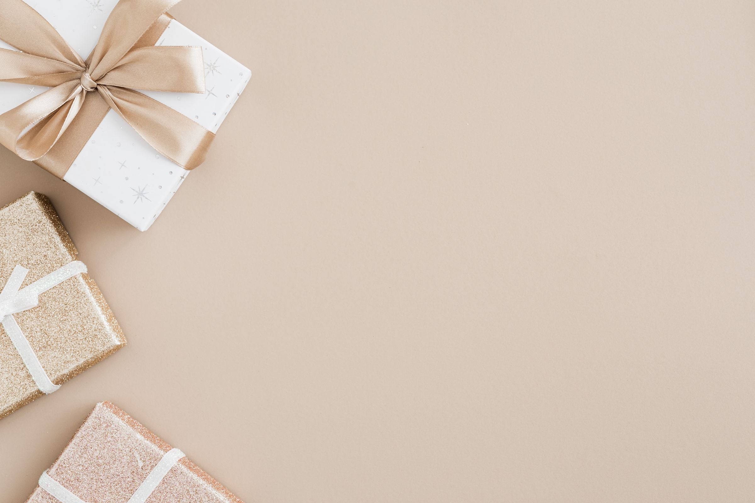 Elegant wrapped gift boxes on a warm beige background